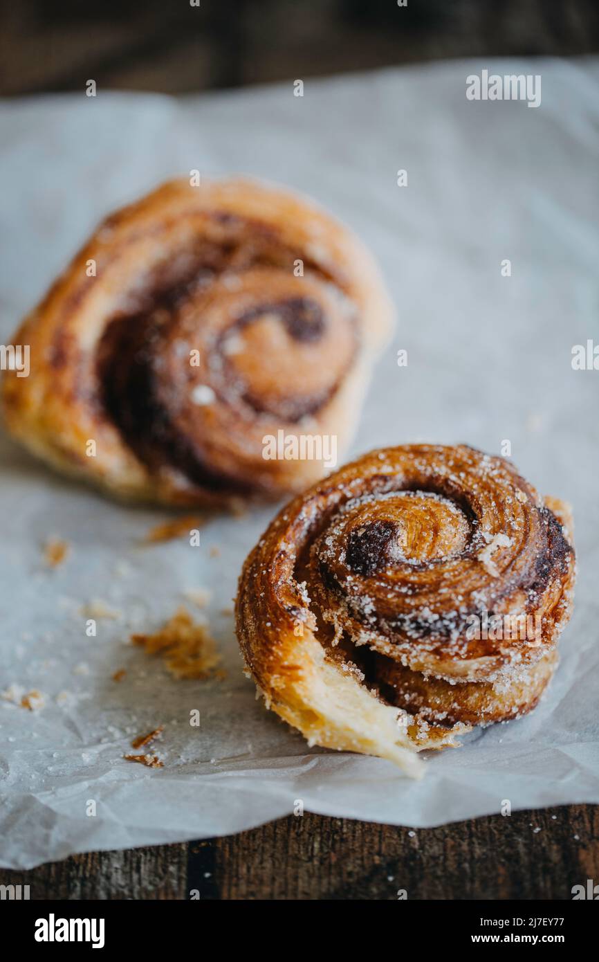 Due dolci alla cannella zuccherati su una pergamena da forno Foto Stock