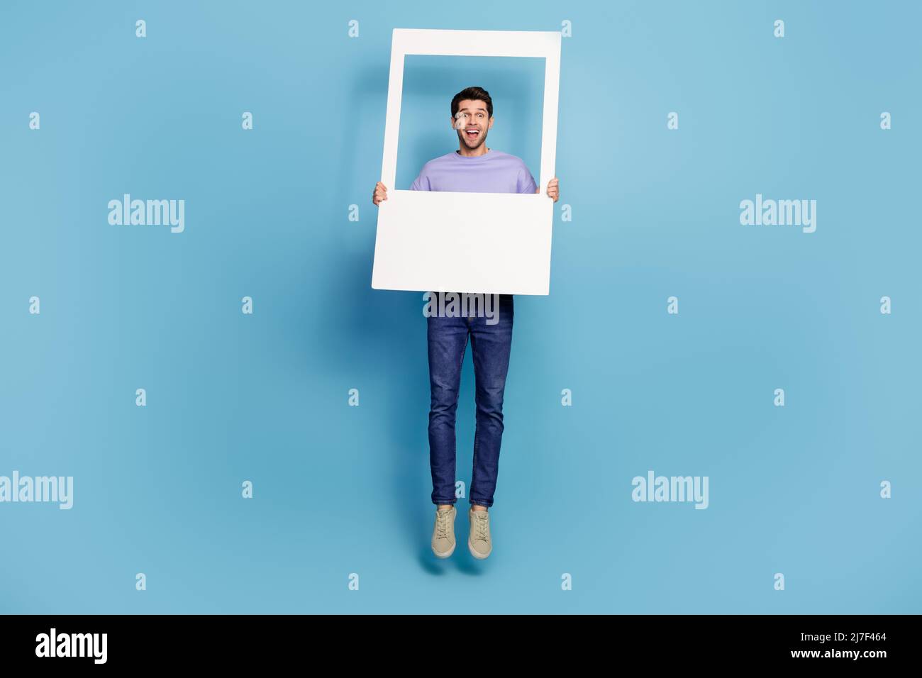 Vista completa della dimensione del corpo del ragazzo attraente che salta struttura di tenuta che ha divertimento isolato su sfondo blu brillante Foto Stock