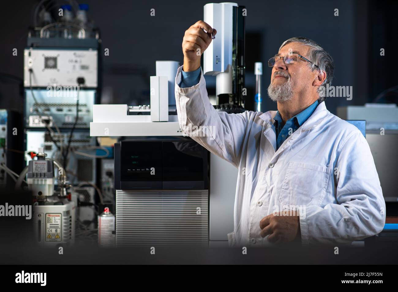 Senior Scientist in un laboratorio di chimica effettuando ricerche - guardando la gas cromatografia campioni, preparare l'analisi su un moderno chromatograp gas Foto Stock
