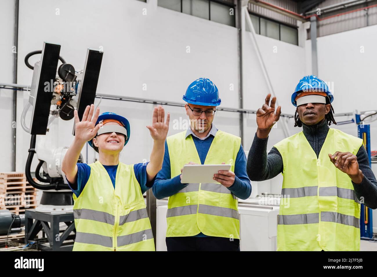 Ingegneri multirazziali che utilizzano occhiali futuristici in realtà aumentata all'interno di una fabbrica di automazione e robotica - nuovo concetto di tecnologia industriale Foto Stock