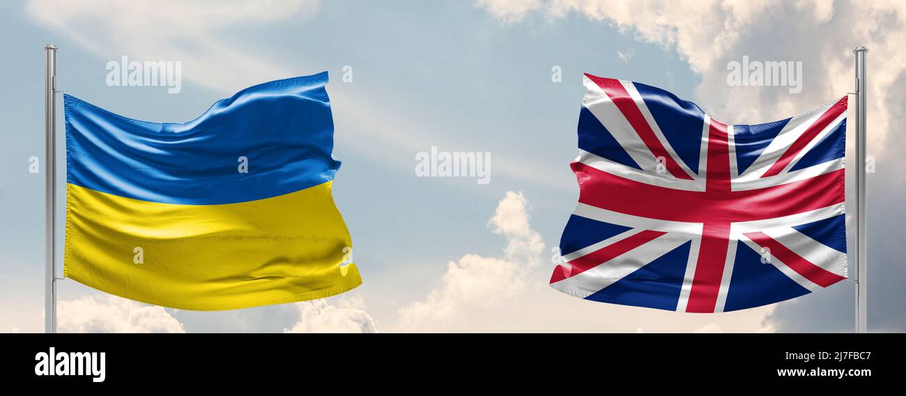 Ucraina e Regno Unito due bandiere su flagpoli e cielo blu. Aiuto militare in ucraina Foto Stock