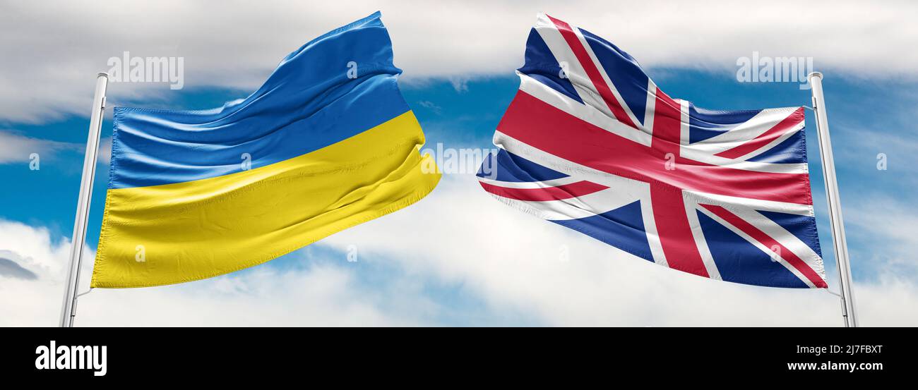 Ucraina e Regno Unito due bandiere su flagpoli e cielo blu. Aiuto militare in ucraina Foto Stock
