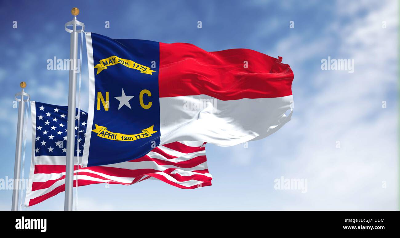 La bandiera di stato del North Carolina sventola insieme alla bandiera nazionale degli Stati Uniti d'America. Sullo sfondo c'è un cielo limpido. Carol nord Foto Stock