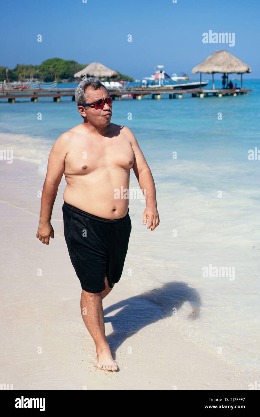 uomo grasso che cammina sulla spiaggia Foto Stock