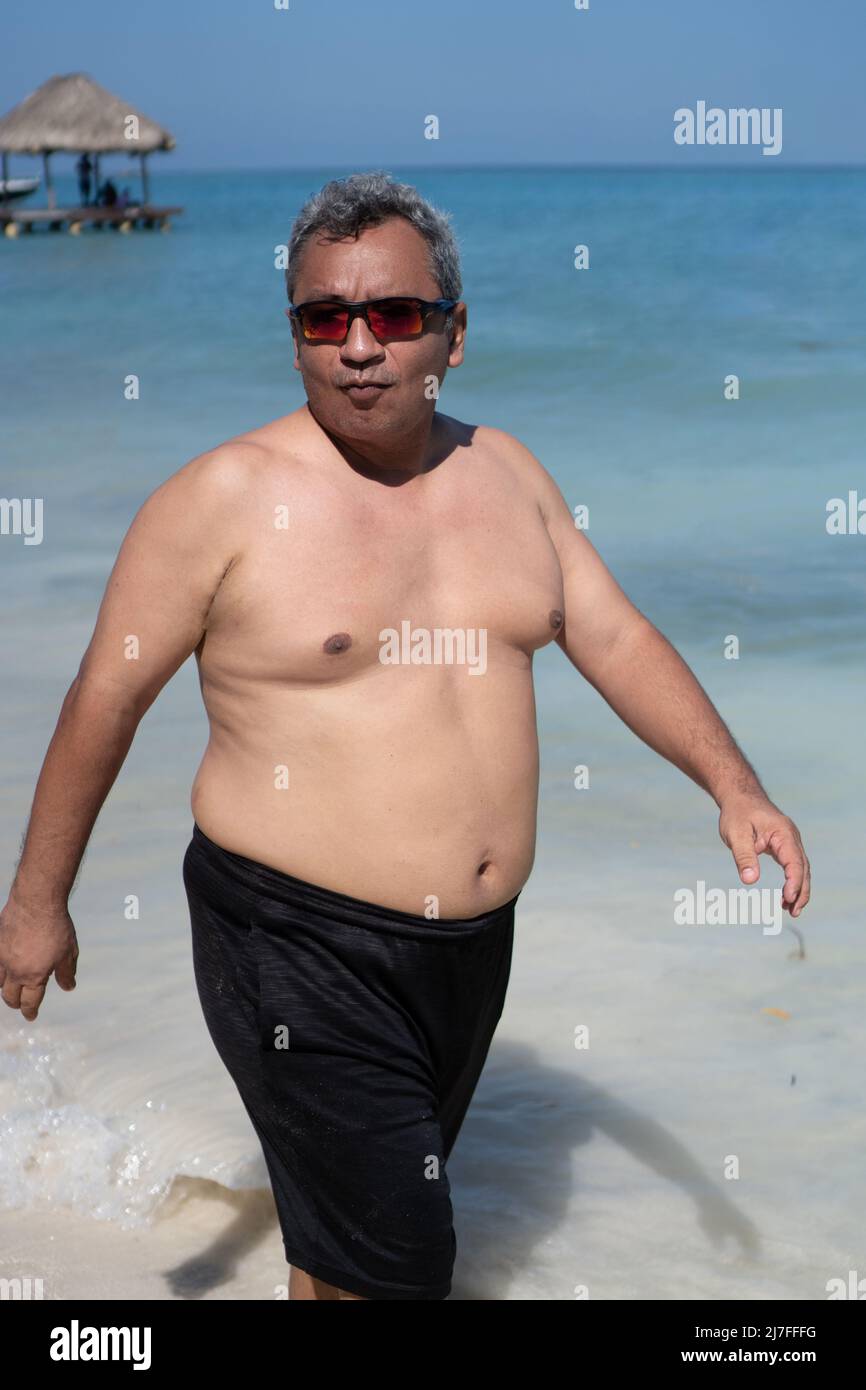 Uomo grasso con grande stomaco a piedi sulla spiaggia Foto Stock