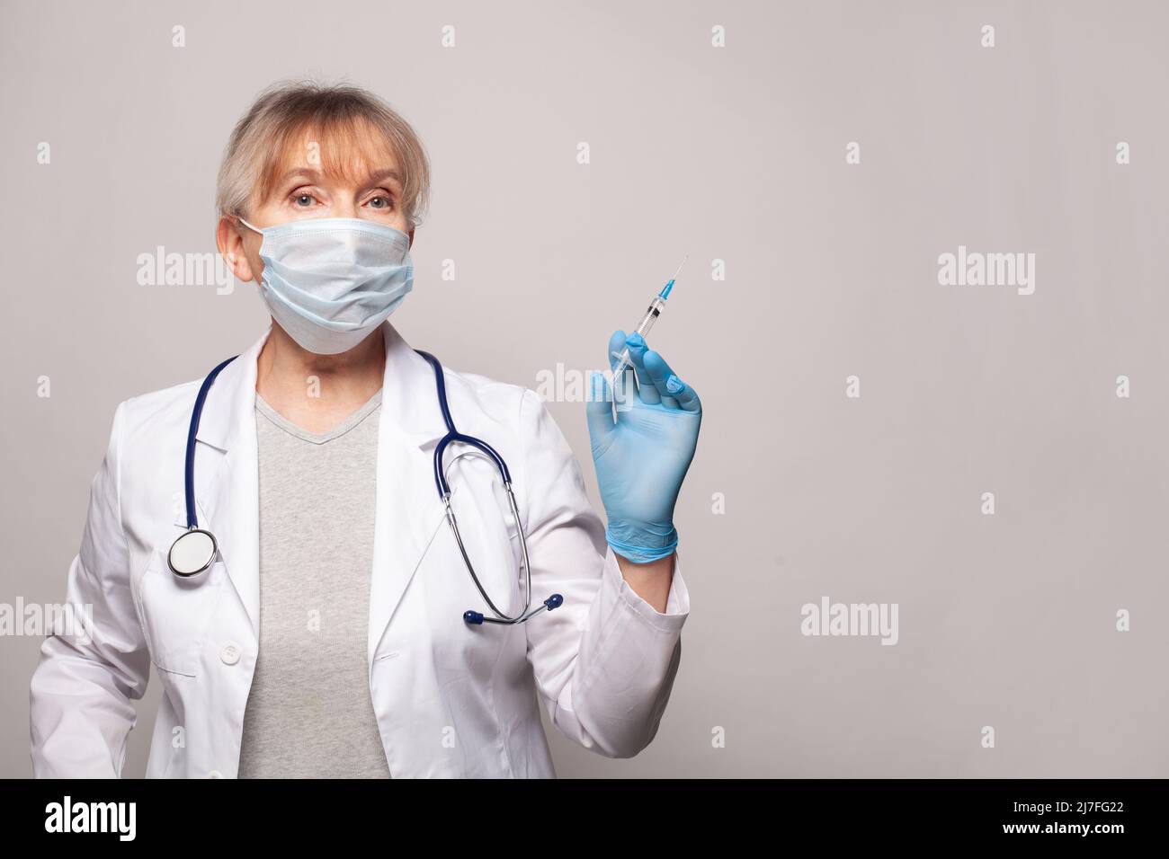 Donna infermiere o medico con siringa. Operatore medico in guanti in nitrile bianco uniforme e blu Foto Stock