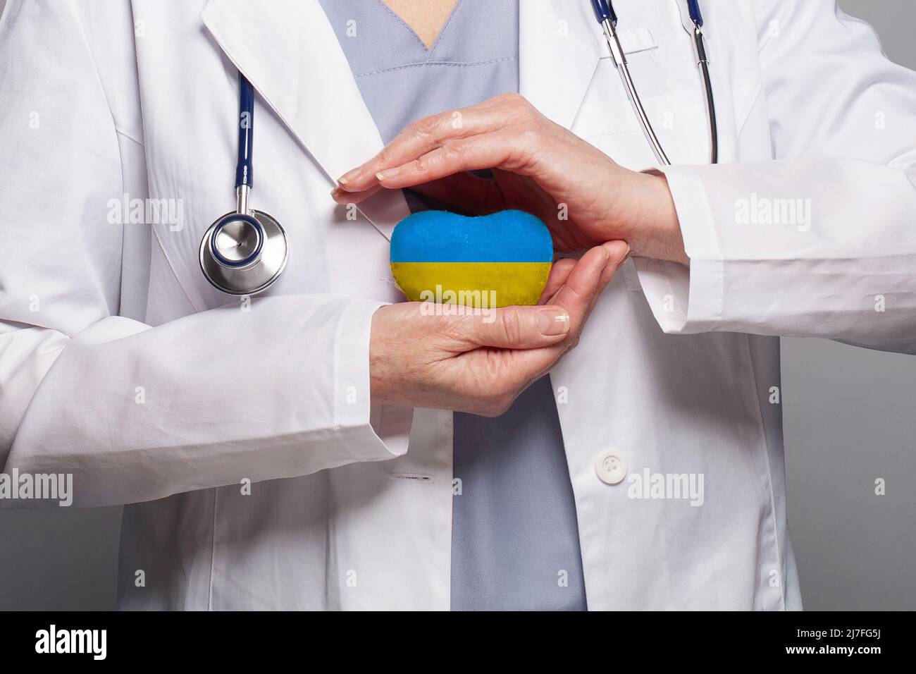 Il medico tiene le mani e cura il cuore con il colore della bandiera Ucraina. Concetto di sicurezza, assistenza sanitaria e medicina in Ucraina Foto Stock