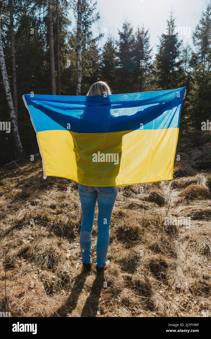 Vista posteriore di una donna che detiene la bandiera Ucraina Foto Stock
