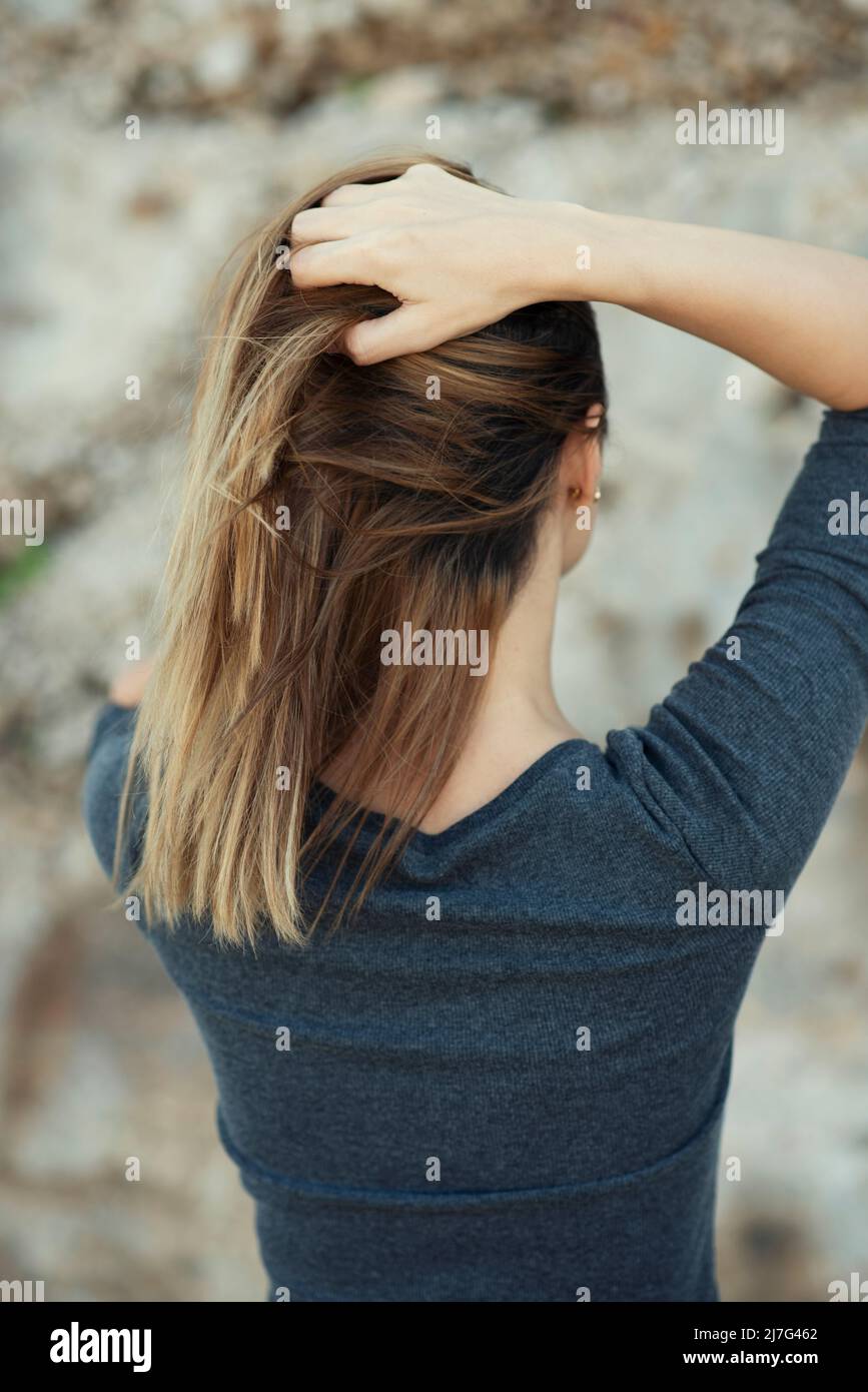 Vista posteriore delle mani della donna nei capelli Foto Stock