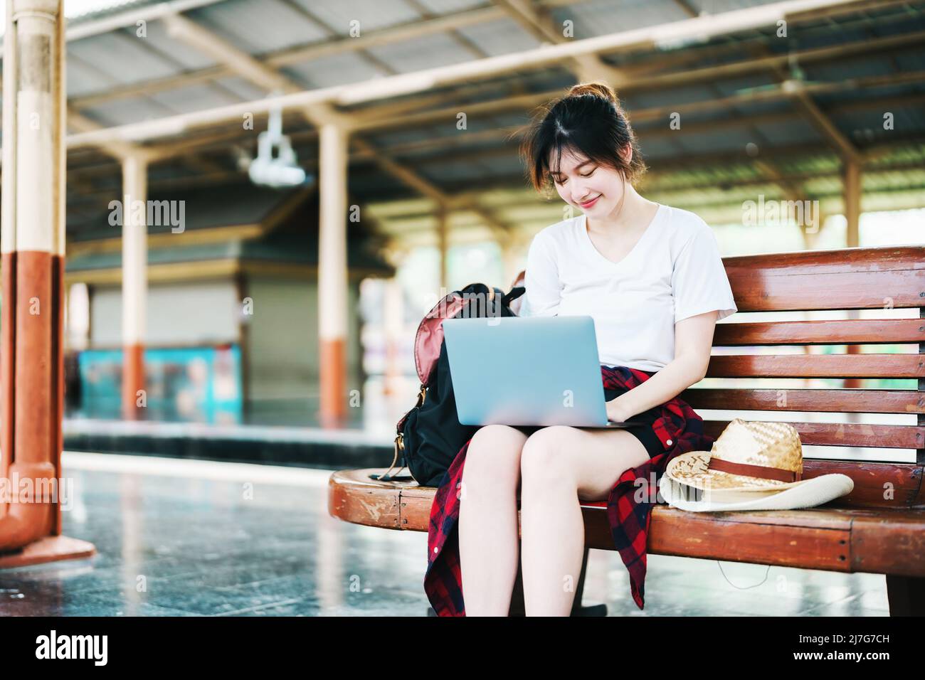 Estate, relax, vacanza, viaggio, ritratto di bella ragazza asiatica utilizzando il computer portatile alla stazione ferroviaria, in attesa del loro tempo di viaggio. Foto Stock