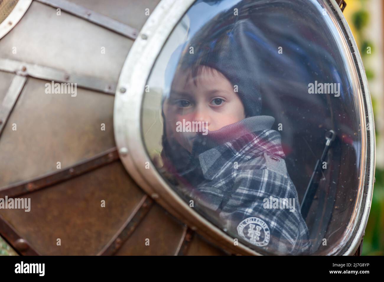 Giovane ragazzo che guarda verso di te attraverso la finestra di un'attrazione carosello. Bruxelles Foto Stock