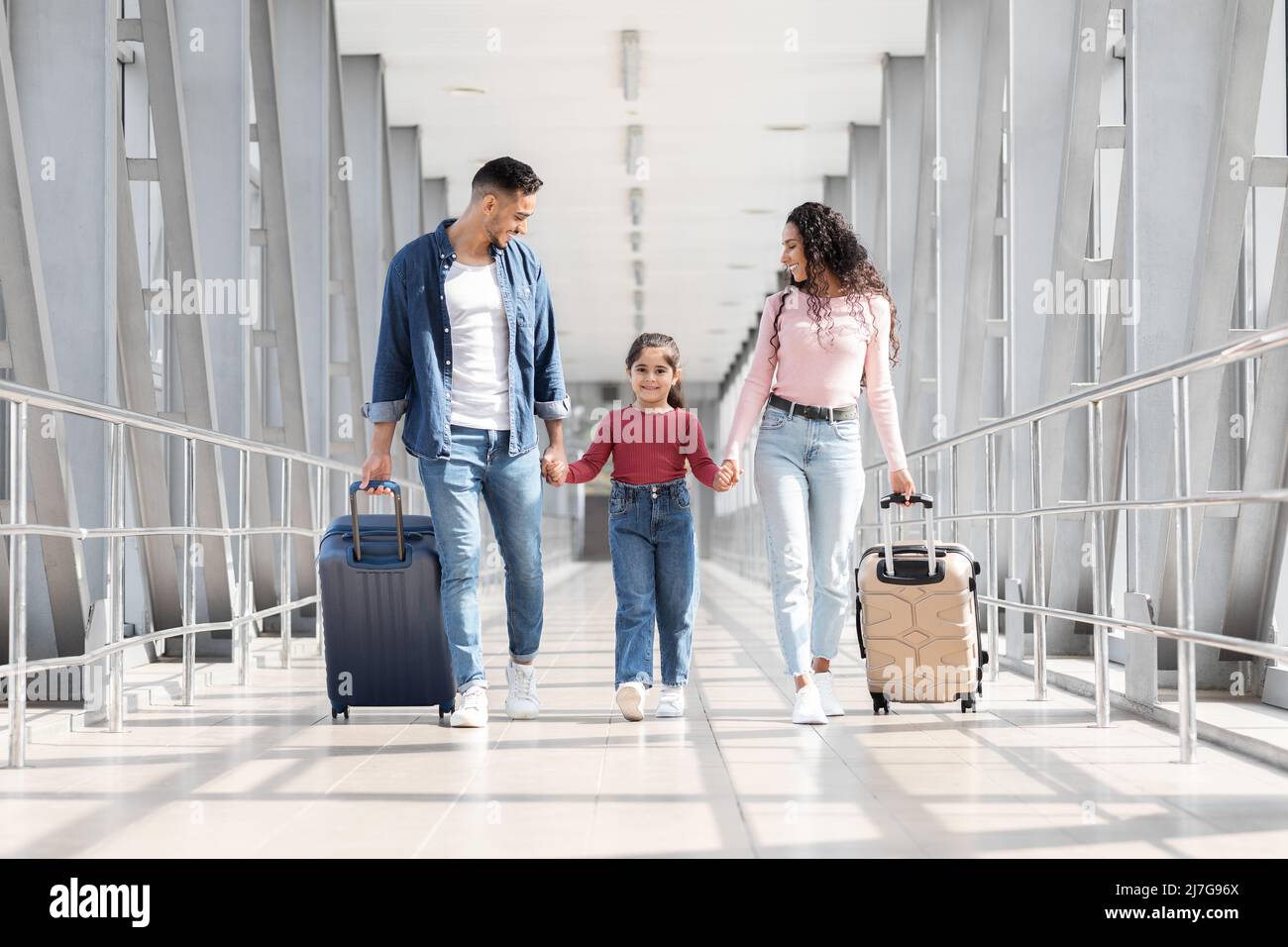 Viaggiare insieme. Gioiosa passeggiata in famiglia araba con valigie al Terminal dell'Aeroporto Foto Stock
