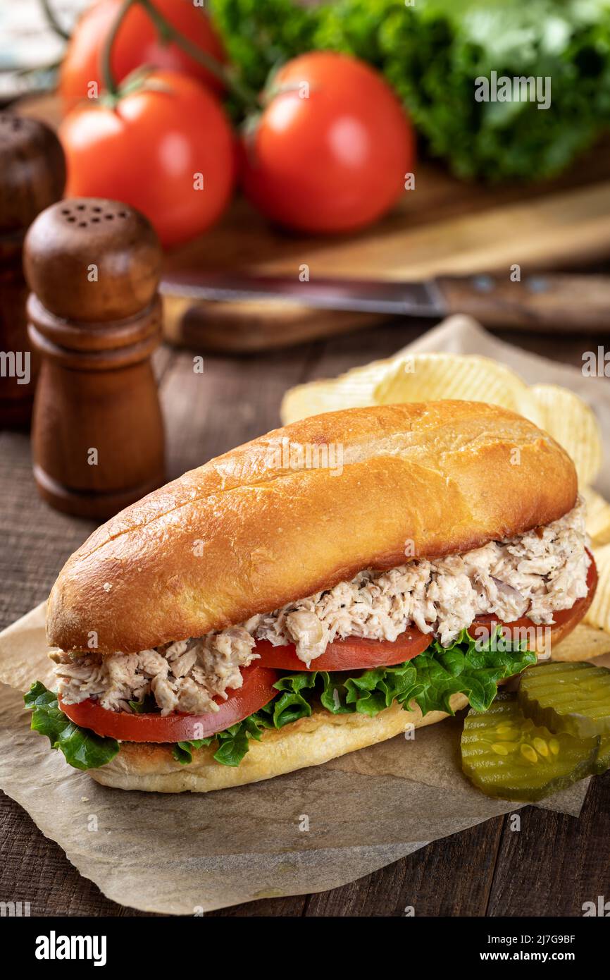 Insalata di tonno, lattuga e sandwich sottomarino al pomodoro con sottaceti e patatine fritte Foto Stock