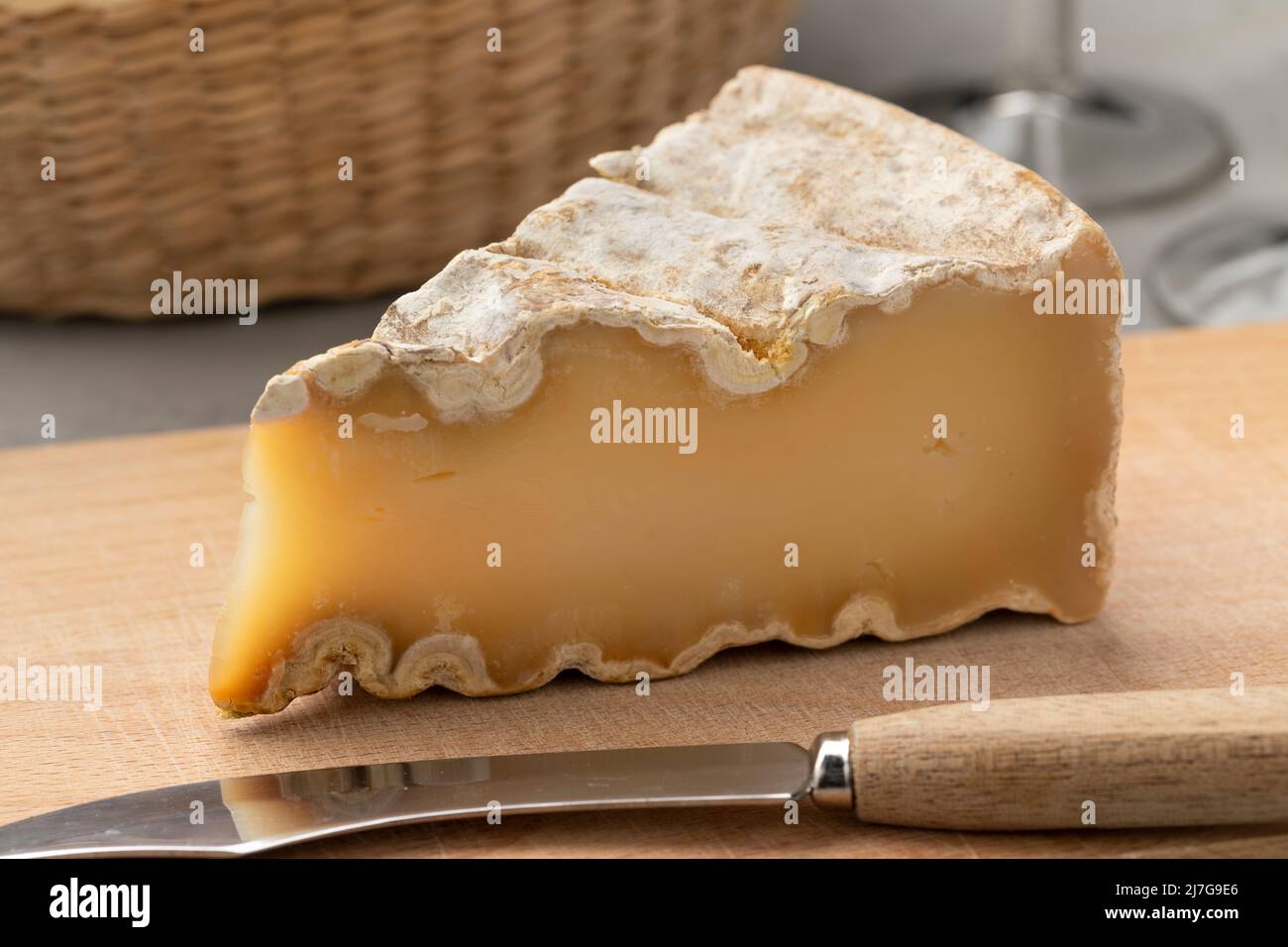 Pezzo di vecchio formaggio dell'abbazia di montagna francese su un tagliere da vicino Foto Stock