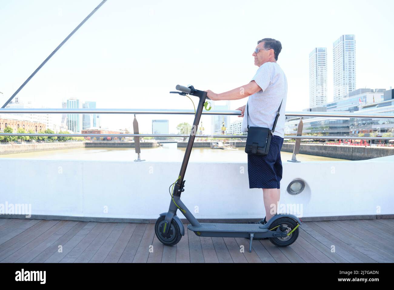 Ispanico uomo anziano giro turistico a Puerto Madero, Buenos Aires, Argentina, con il suo scooter elettrico del calcio. Concetti: Viaggiare e godersi l'outdoo Foto Stock