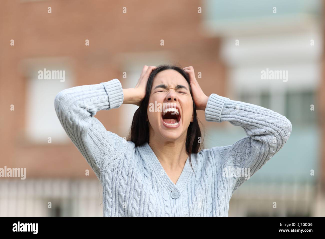 Ritratto della vista frontale di una donna pazza che urla per strada Foto Stock