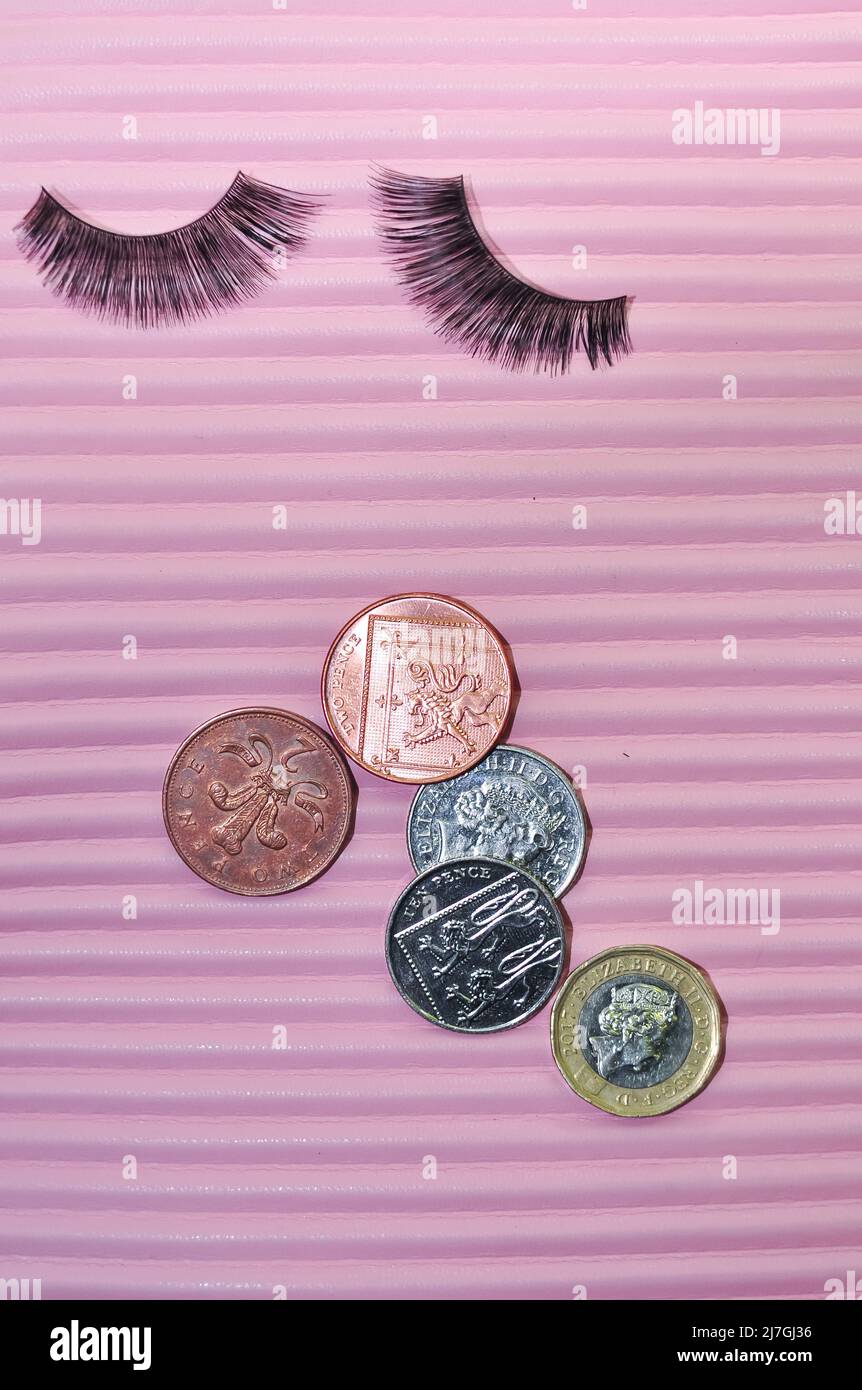 Fiocchi e monete in sterline su sfondo rosa, concetto di prezzo Foto Stock