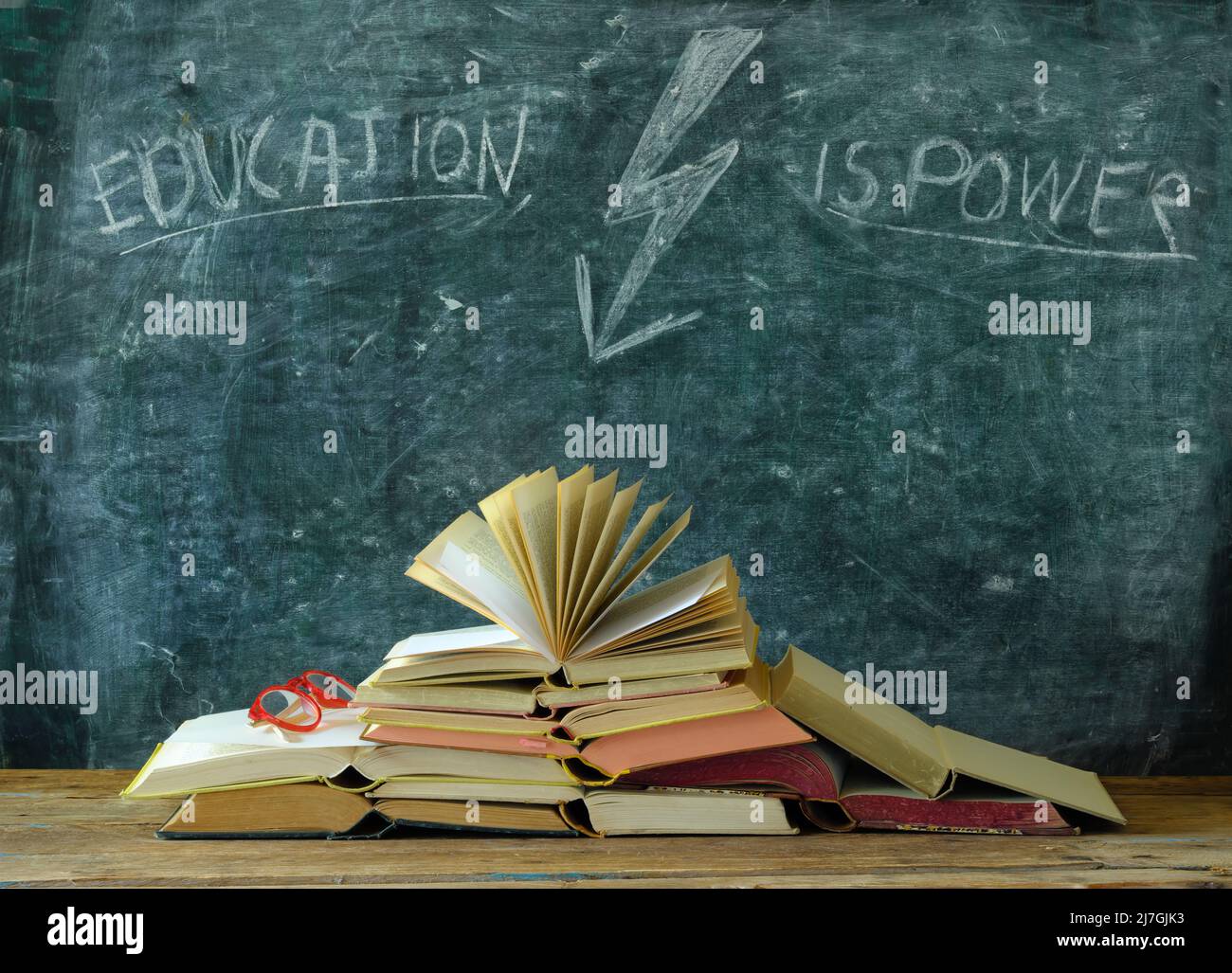 libro aperto di fronte a una lavagna con disegno di un fulmine e slogan istruzione è potere, apprendimento, conoscenza e concetto di scuola Foto Stock