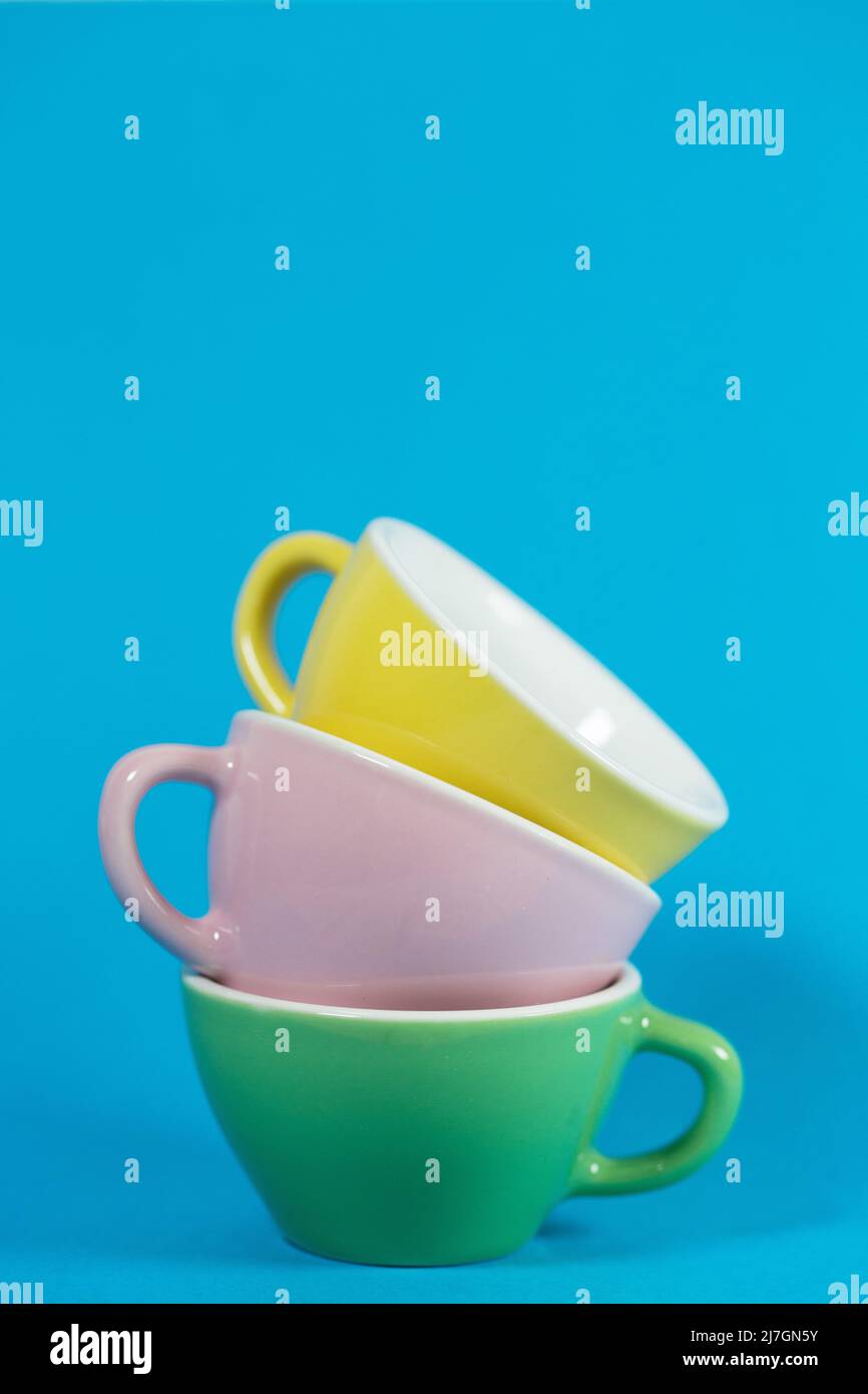 Una pila di teacup color pastello su sfondo blu. Foto Stock