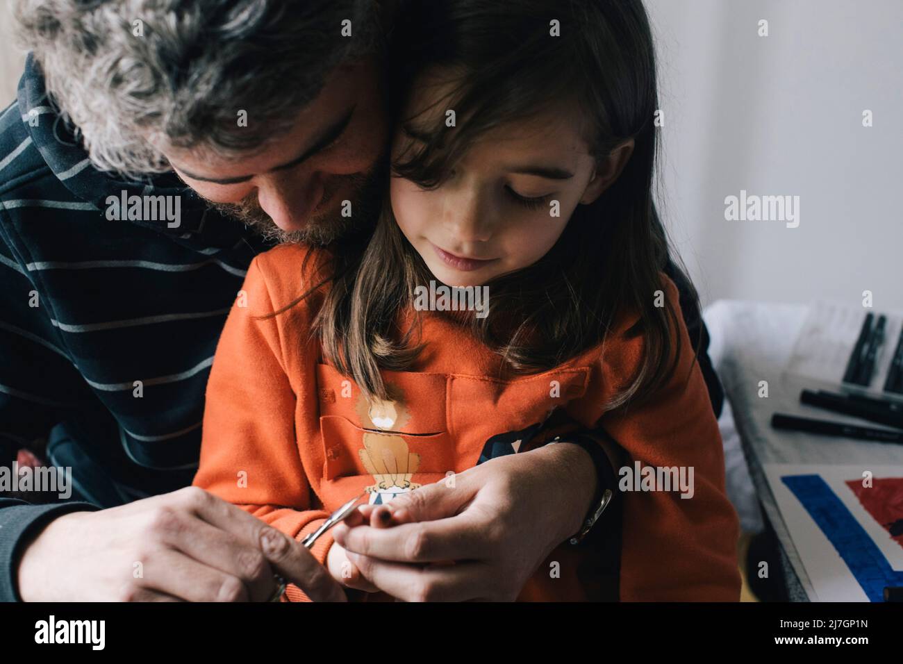 Padre tagliando chiodi di figlia con forbici a casa Foto Stock