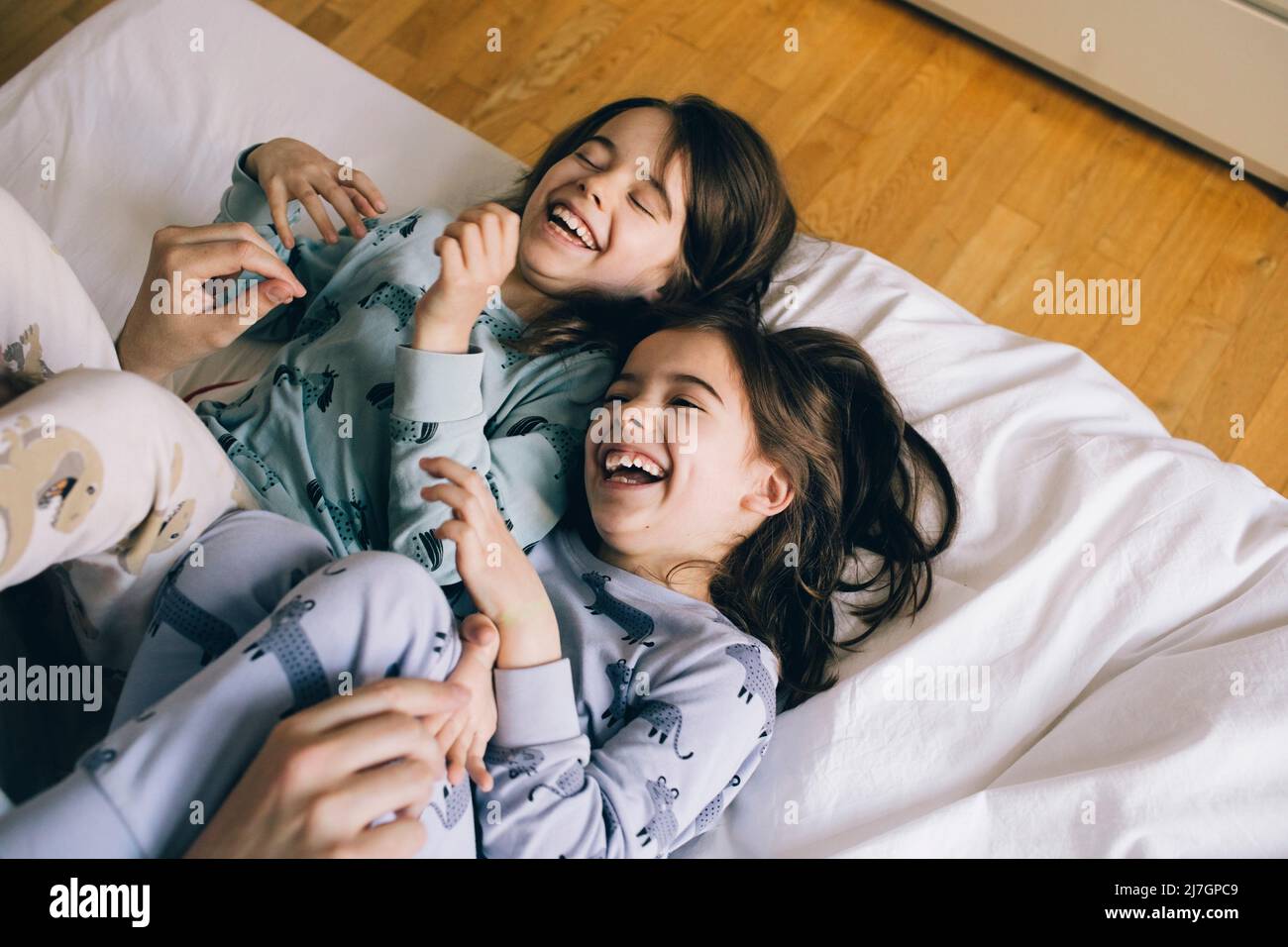 Le ragazze gemelle ridono mentre sdraiati sul letto a casa Foto Stock