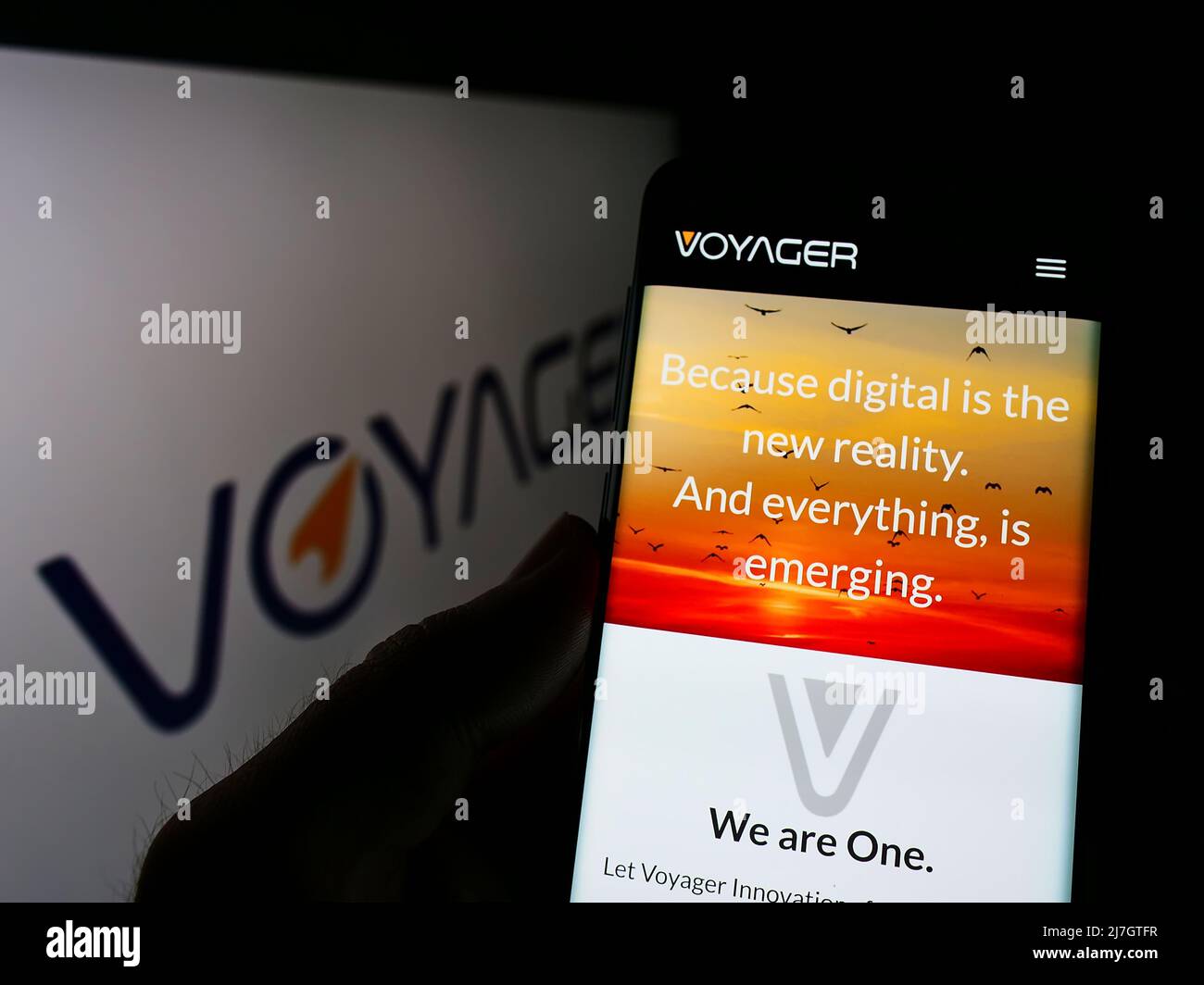 Persona che tiene lo smartphone con la pagina web della società filippina Voyager Innovations Inc. Sullo schermo davanti al logo. Concentrarsi sul centro del display del telefono. Foto Stock