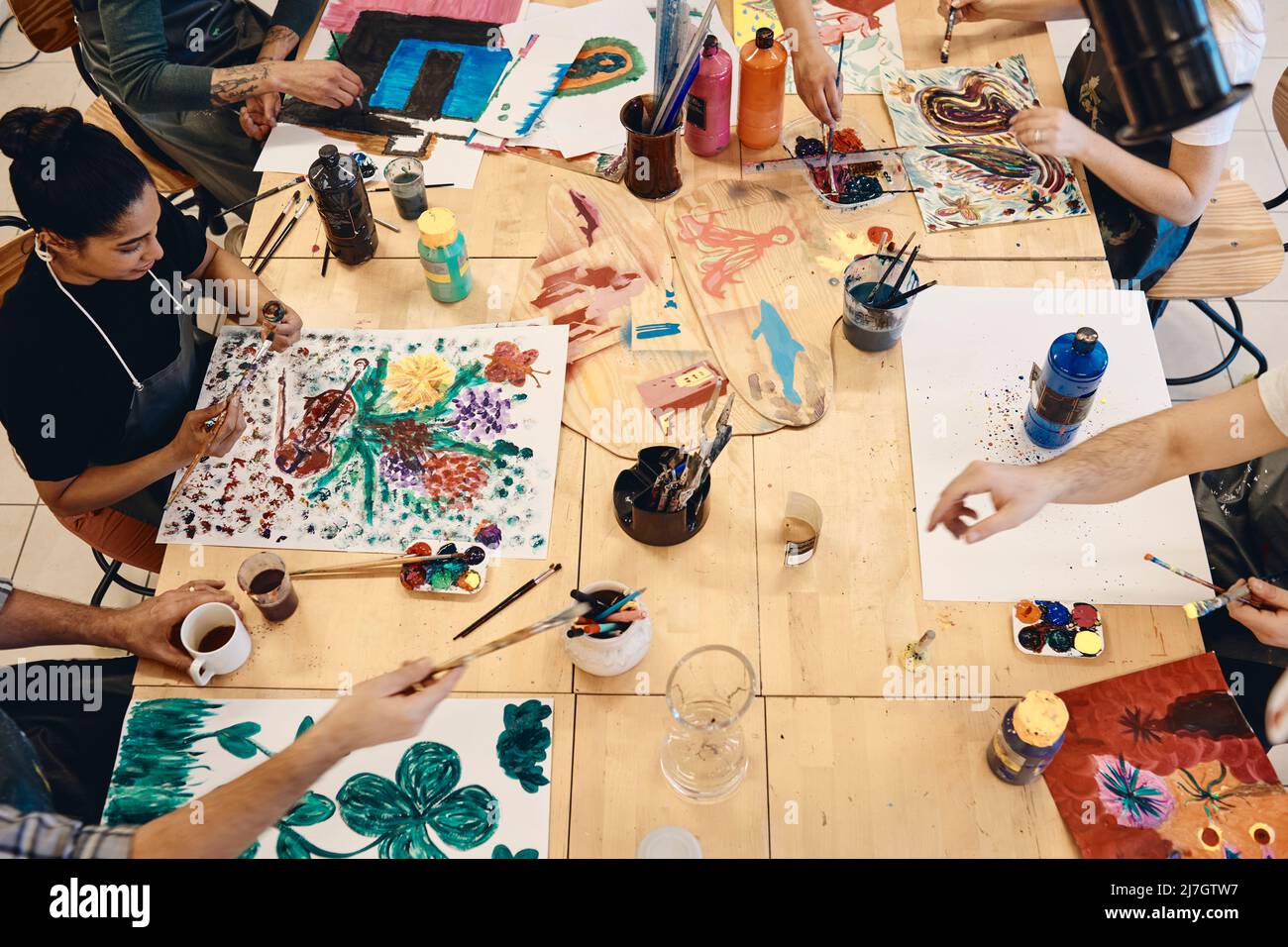 Vista ad alto angolo degli studenti che praticano la pittura al tavolo in classe d'arte Foto Stock