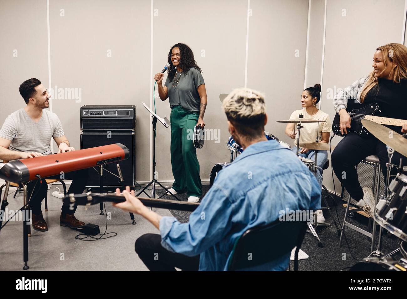 Felici uomini e donne multirazziali che guardano amici cantare durante le prove in classe Foto Stock