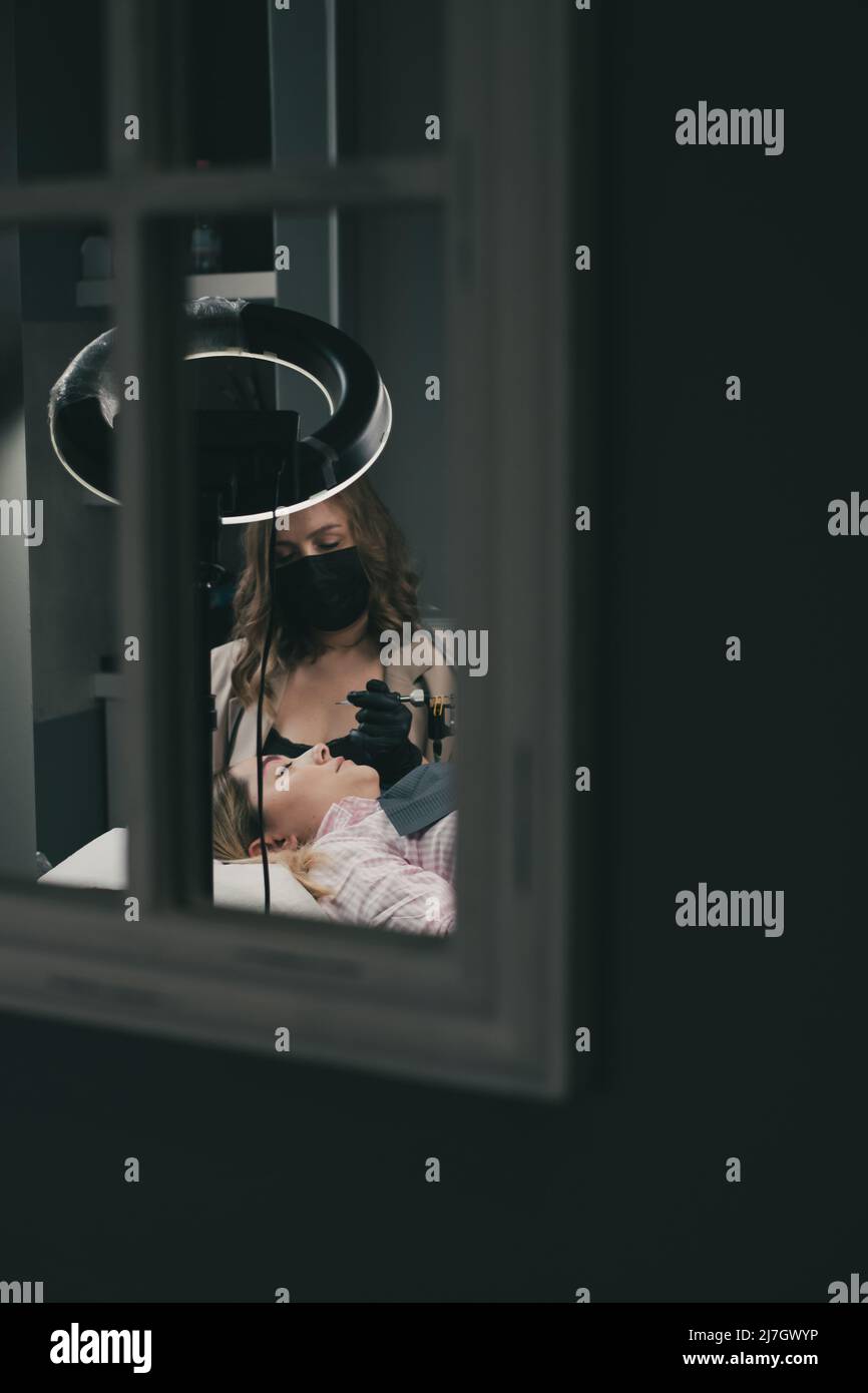 Cosmetologo che applica permanente compongono le sopracciglia per un cliente Foto Stock