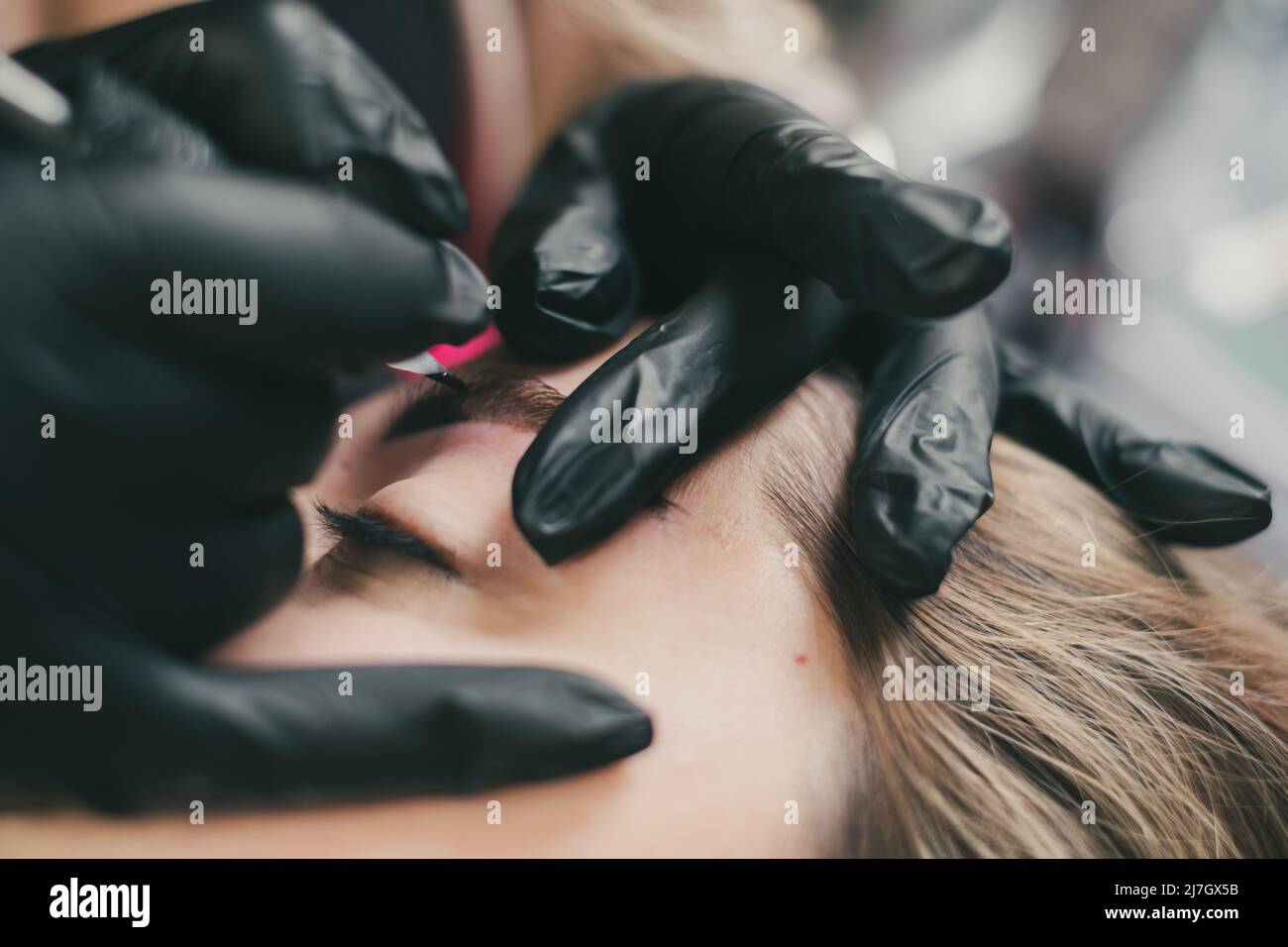 Cosmetologo che applica permanente compongono le sopracciglia per un cliente Foto Stock
