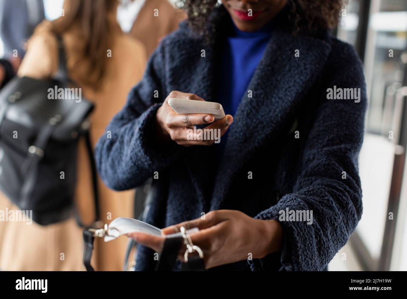 Metà sezione di donna d'affari fotografando la carta d'identità attraverso lo smartphone al seminario Foto Stock