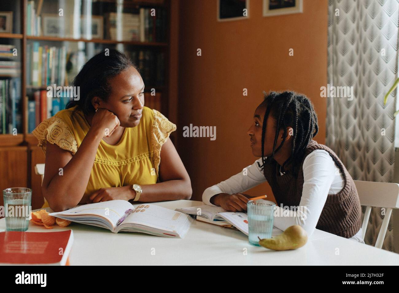 Madre e figlia si parlano mentre studiano a casa Foto Stock