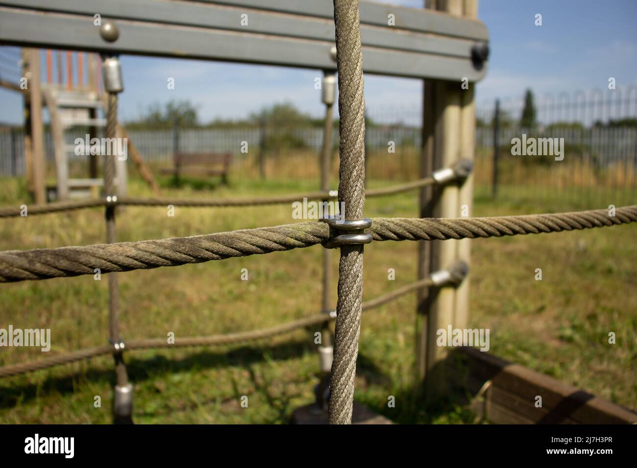 primo piano dell'attrezzatura per l'arrampicata su corda e filo in una parco giochi per bambini con recinzione di sicurezza Foto Stock