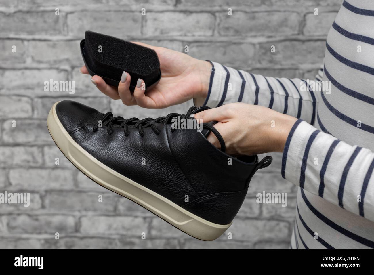 donna strofinando le sue scarpe nere con una spugna. Foto di alta qualità Foto Stock