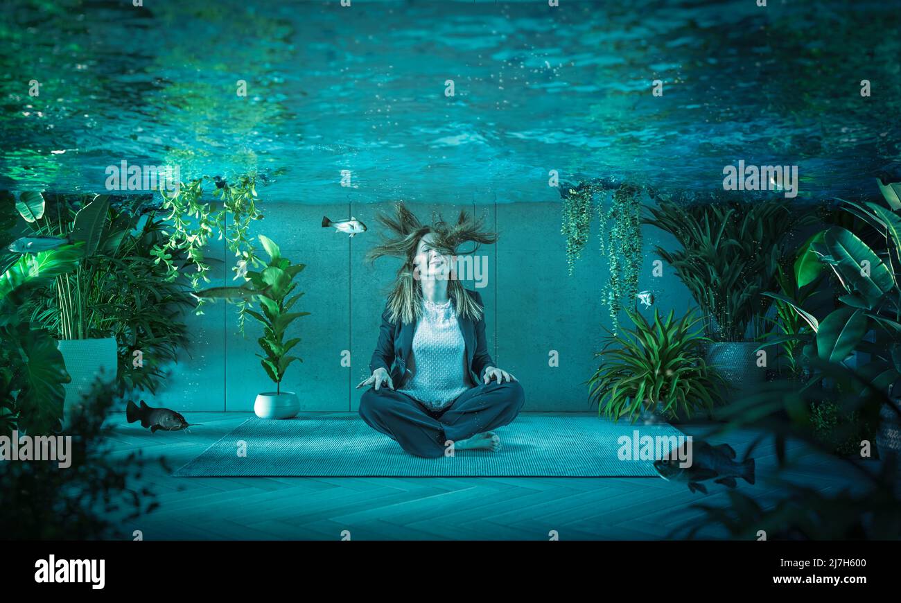 la donna si rilassa sott'acqua in una stanza piena di pesce. Foto Stock