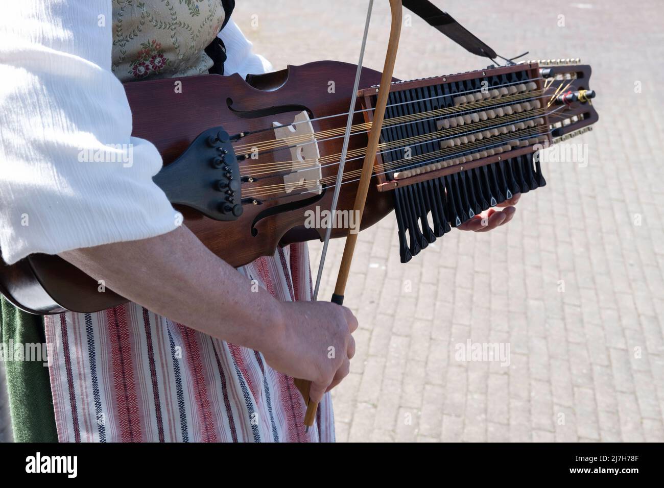 Donna in costume tradizionale svedese suona musica folk su una nyckelharpa svedese in primo piano con particolare attenzione all'arco, agli archi e all'arco Foto Stock