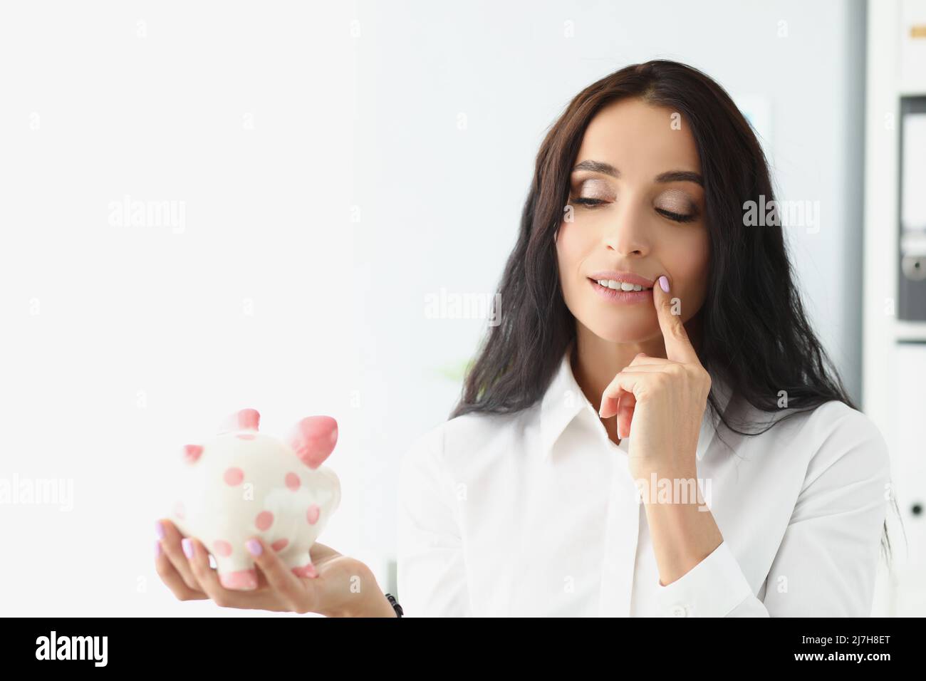 Donna tenere piggybank, pensare al modo migliore di utilizzare i soldi, risparmiare per il futuro Foto Stock