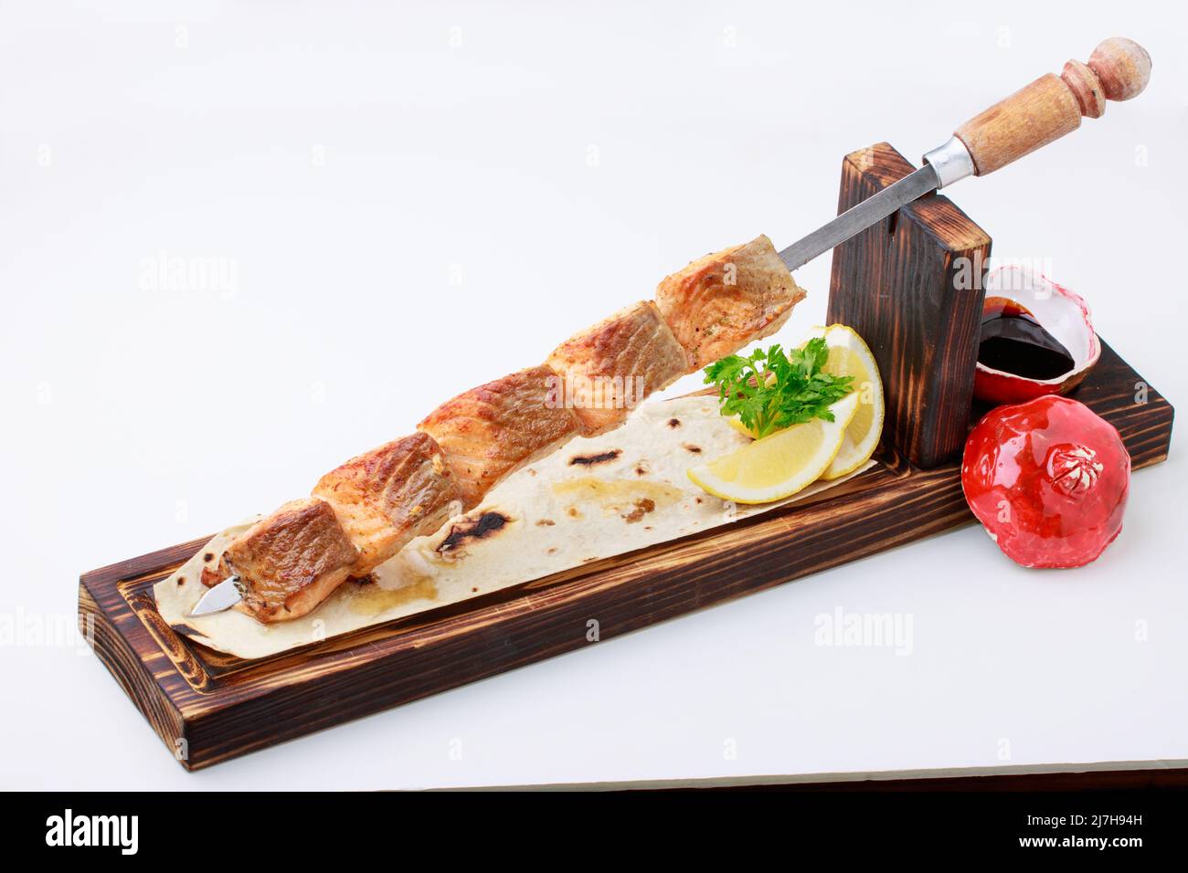 Salmone alla griglia su spiedini di acciaio inossidabile, servito su pane piatto con salsa di limone e Pomegrenate. Isolato su sfondo bianco. Foto Stock