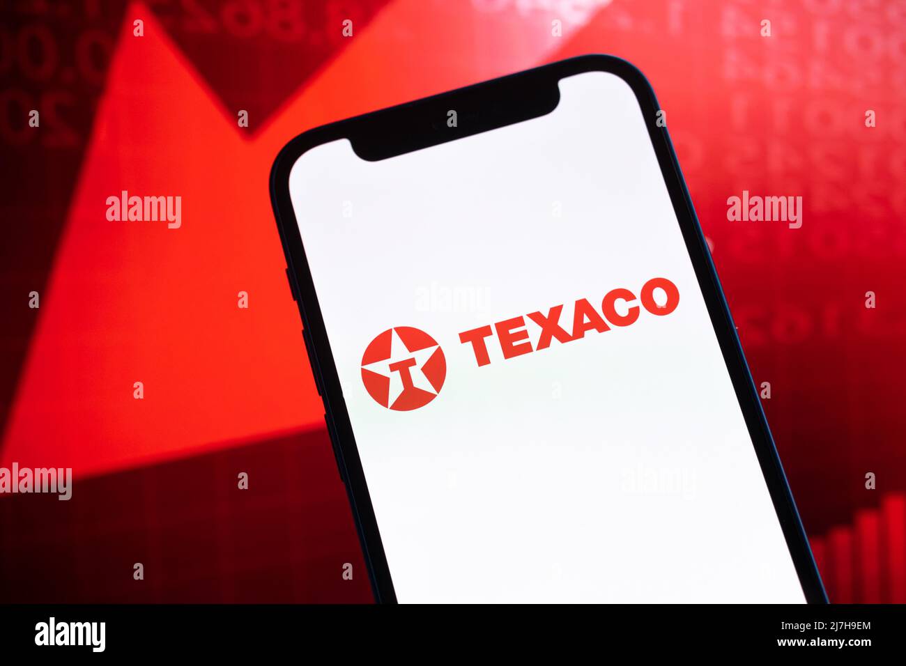 Prezzi olio Texaco, primo piano logo. Crolli, crisi petrolifera, freccia rossa in basso sullo sfondo dei grafici del mercato azionario Foto Stock