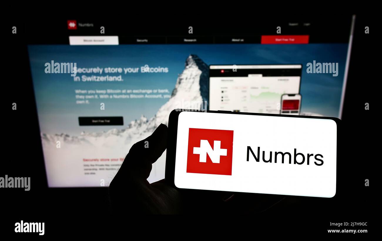 Persona che tiene uno smartphone con il logo della società FinTech Numbrs Personal Finance AG sullo schermo di fronte al sito web. Mettere a fuoco sul display del telefono. Foto Stock