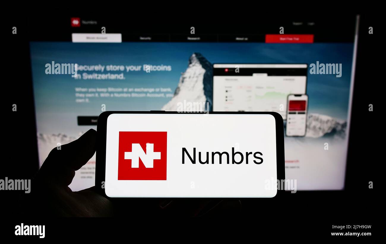 Persona che tiene il cellulare con il logo della società FinTech Numbrs Personal Finance AG sullo schermo di fronte al sito web aziendale. Mettere a fuoco sul display del telefono. Foto Stock