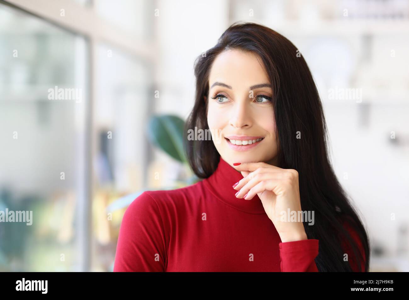 Signora giovane attraente con taglio di capelli brunette in posa con aspetto pensivo Foto Stock