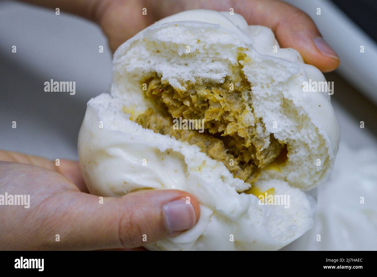 Cuccette cinesi a vapore a mezza apertura (cha siu bao) in un piatto, che mostra il ripieno di verdure di carne all'interno. Foto Stock