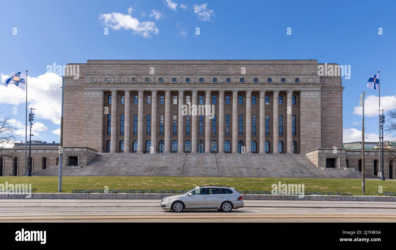 Bandiera finlandese che vola di fronte all'edificio del parlamento finlandese a Helsinki Foto Stock