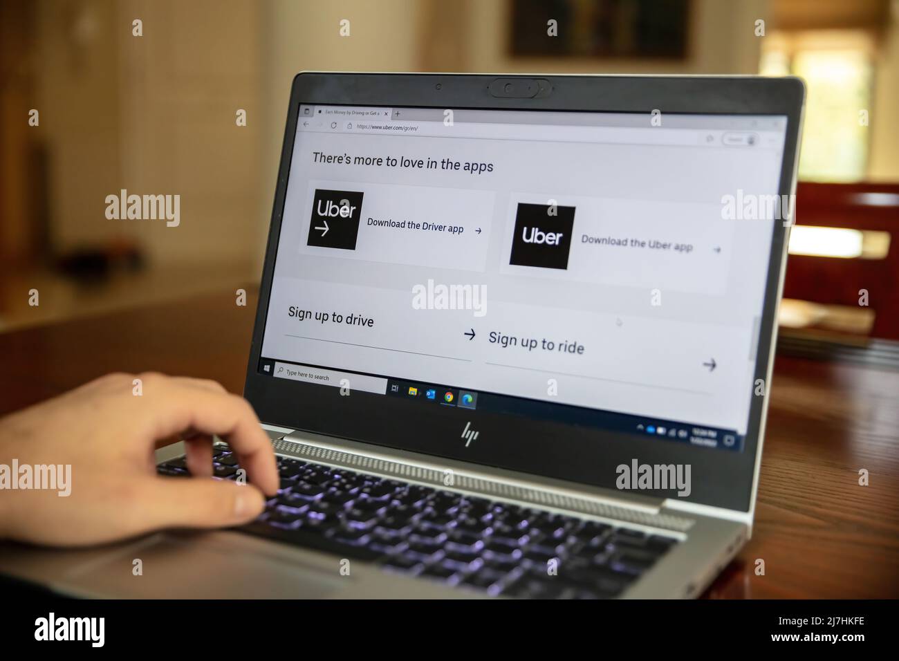 Grecia, Atene, gennaio 23 2022. TAXI UBER. Ordine online per taxi. Laptop sul tavolo, mano della persona sulla tastiera, app del servizio di trasporto sullo schermo. Foto Stock