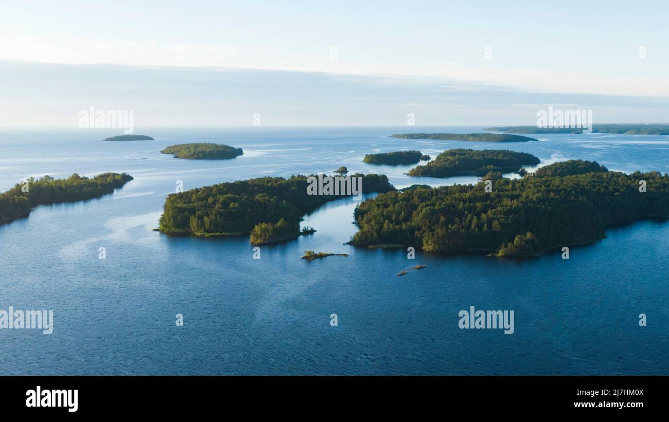 Piccole isole rocciose con una foresta nel mezzo di un grande lago in estate all'alba vista aerea Foto Stock