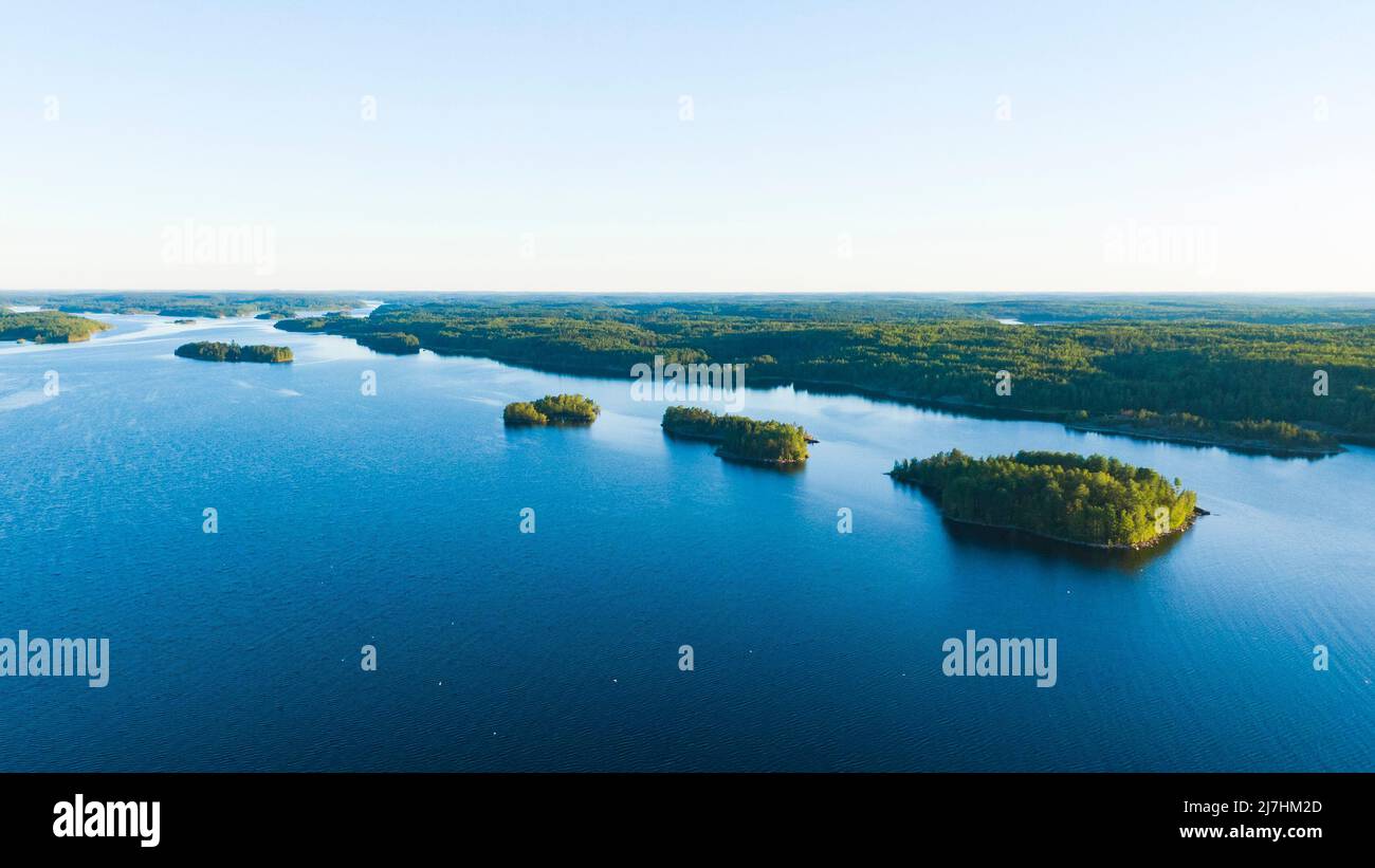 Piccole isole rocciose con una foresta nel mezzo di un grande lago in estate all'alba vista aerea Foto Stock