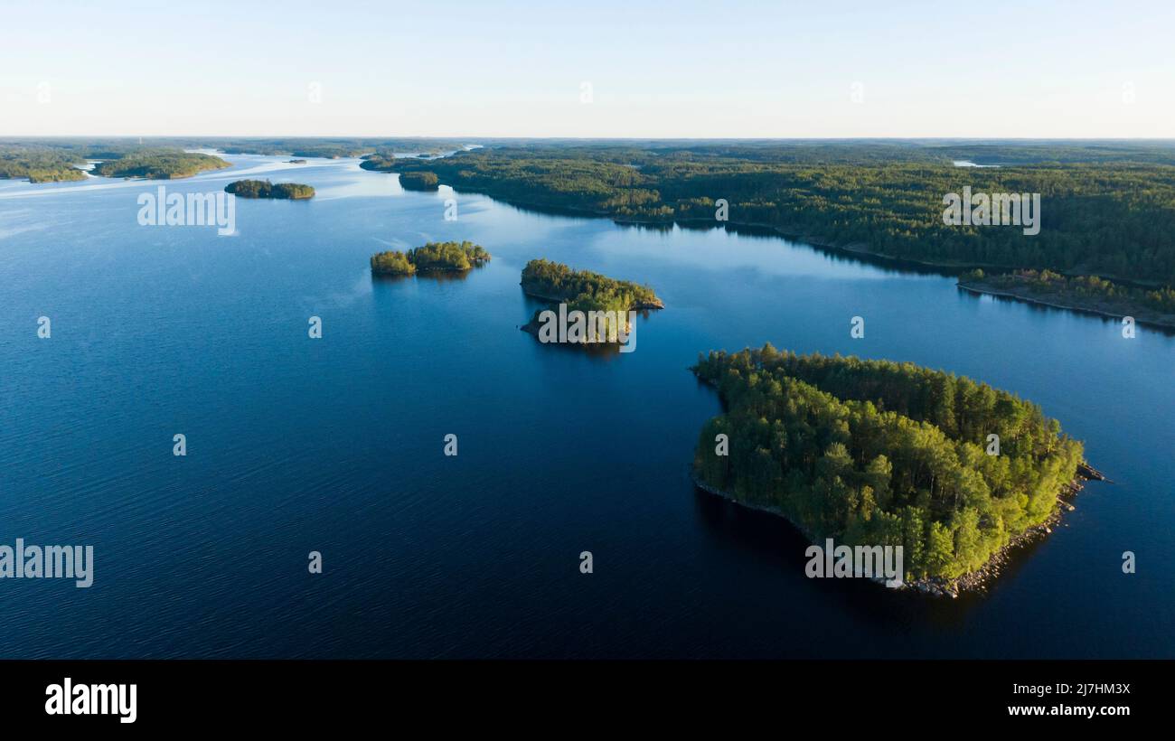 Piccole isole rocciose con una foresta nel mezzo di un grande lago in estate all'alba vista aerea Foto Stock