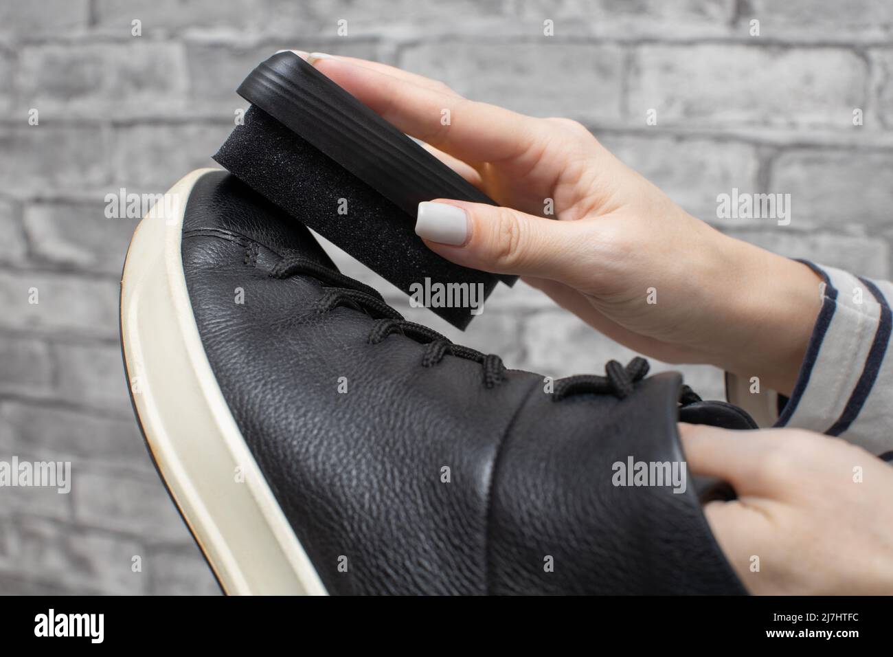 donna strofinando le sue scarpe nere con una spugna. Foto di alta qualità Foto Stock