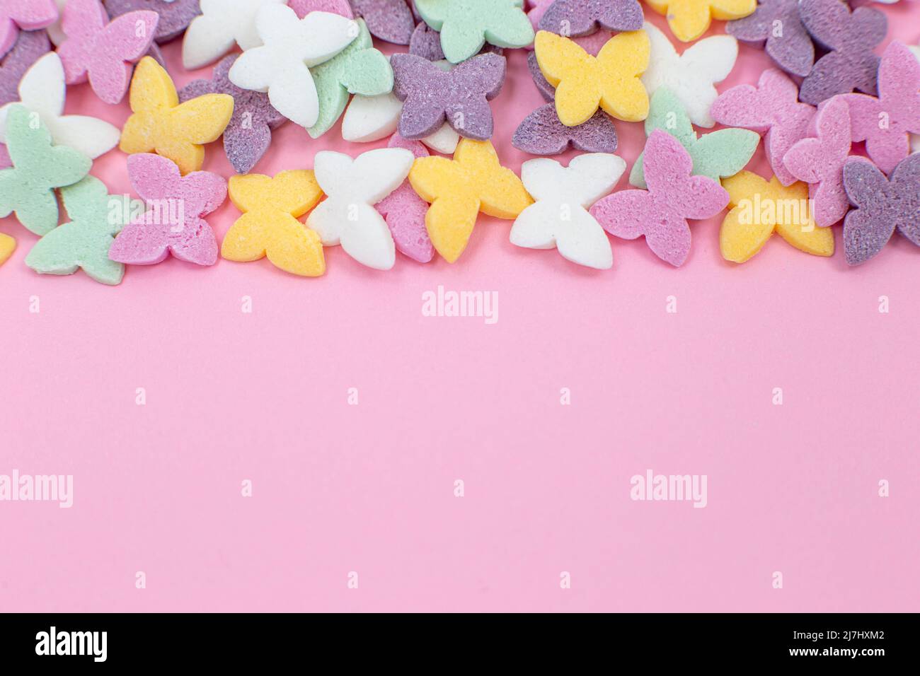 Le farfalle colorate, le famose caramelle di zucchero spolverate, giacciono su uno sfondo rosa. Foto Stock